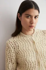 Cardigan de punto calado color beige, con cuello redondo y cierre frontal de botones.