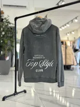 Canguro oversize de color marrón, con capucha y estampa en la espalda con el texto "Official Member of Top Style Club".