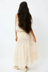 Pollera maxi de gasa color beige con efecto arrugado, con sección de punto smock en la cintura y diseño de volados escalonados en la parte inferior.