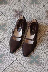 Mocasines de cuero color marrón chocolate, con punta fina y tira sobre el empeine con hebilla metálica.