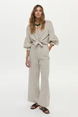 Pantalón de lino color beige, de corte ancho y relajado, con cintura alta y bolsillos laterales.