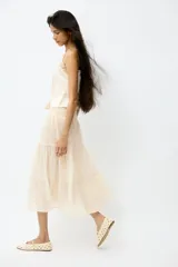 Pollera maxi de gasa color beige con efecto arrugado, con sección de punto smock en la cintura y diseño de volados escalonados en la parte inferior.
