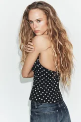 Top negro con estampado de lunares blancos, escote halter y diseño estructurado tipo corset con copas fruncidas en el centro.
