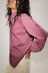 Camisa de manga larga con cuello solapa, cierre frontal con botones y bajo asimétrico, con estampado de rayas verticales.