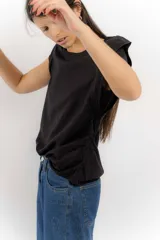 Remera negra sin mangas con hombreras marcadas y detalle de fruncido lateral. Confeccionada en una mezcla de tencel y lino.