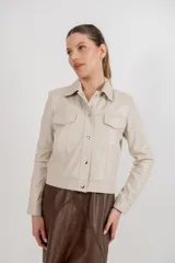 Campera estilo jeanera confeccionada en cuero ovino, con corte recto y largo a la cintura. Presenta cierre frontal con botones metálicos a presión, cuello clásico y dos bolsillos frontales con tapa.