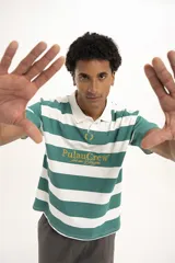 Remera de manga corta color verde oscuro, estilo polo con cuello y abertura frontal. Presenta un bordado central con el texto "PulauCrew" y un laurel en la parte superior.