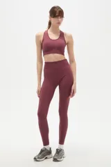Calza deportiva de tiro alto y ajuste ceñido al cuerpo, confeccionada en tejido elástico de color bordó.