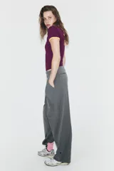 Pantalón de tiro alto con diseño de rayas verticales, corte recto y holgado. Presenta pliegues frontales, bolsillos laterales y bajo ajustable con botón.
