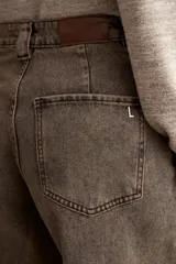 Jean culotte de tiro alto y corte ancho, color marrón chocolate con efecto lavado. Presenta costuras verticales frontales, bolsillos laterales y cierre con botón y cremallera.