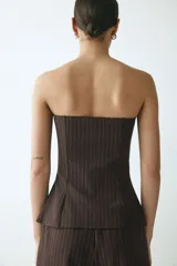 Chaleco strapless de punto pesado con patrón de rayas finas, escote recto con reborde oculto de silicona y botonadura frontal de cinco botones.
