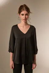 Blusa de satén color negro con cuello en V, mangas tres cuartos y detalle de pliegue central en el frente.