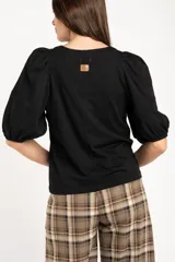 Remera de algodón negro con mangas cortas abullonadas, cuello redondo y costura central frontal.