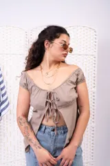 Blusa blanca de manga corta abullonada, con escote corazón y cierre frontal con múltiples lazos para atar.