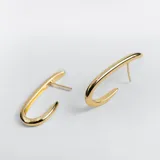 Par de aros dorados grandes, que simulan argollas. Con pasante y fru fru. De diseño ovalado, inflado y liso.