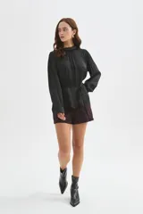 Blusa de poliéster color negro con cuello alto, mangas largas, diseño holgado, detalles de frunces y lazo ajustable en la cintura.