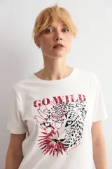 Remera de algodón blanca con estampa frontal de leopardo y texto en color rojo.