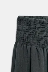 Pantalón baggy de tiro medio color rosado, con cintura elástica fruncida tipo nido de abeja y bajos ajustables con cordones.