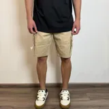 Bermuda cargo de gabardina color beige, con bolsillos laterales con solapa y bolsillos frontales tipo ojal.