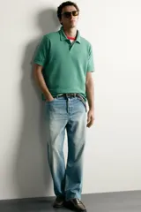 Remera polo regular fit de color gris oscuro, confeccionada en tejido de algodón con textura de rayas verticales. Cuenta con cuello solapa, cierre frontal con botones y mangas cortas con terminación en rib.