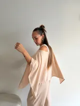 Blusa de lanilla gris con diseño asimétrico de un solo hombro y corte holgado tipo capa.