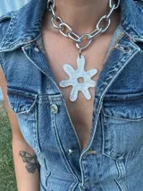 Collar plateado con cadena de eslabones grandes y dije abstracto con forma de flor color negro con glitter. El dije es desmontable.