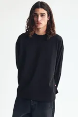 Remera de manga larga en punto pesado, color negro, con cuello redondo ribeteado, hombros caídos y bajo recto. Corte oversized para una silueta amplia y relajada.