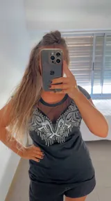 Remera negra de mangas cortas con escote redondo y detalle de tul transparente en la parte superior del pecho. Presenta bordados con lentejuelas plateadas en forma de arabescos. Corte clásico.