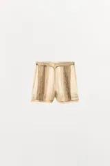 Shorts de tiro medio confeccionados en tejido de organza semitransparente con estampado floral sutil. Presenta diseño con pliegues verticales, aplicaciones bordadas a contraste en el bajo y terminación con puntilla. Cuenta con cierre lateral mediante cremallera oculta.