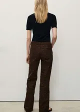 Pantalón de jean con diseño recto y tiro alto, confeccionado en algodón con estampado animal print de cebra en tonos marrones. Cuenta con cierre frontal de cremallera y botón, trabillas para cinturón y cinco bolsillos clásicos.