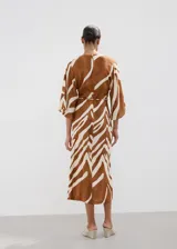 Vestido midi con estampado animal print tipo cebra en tonos marrón y blanco, de corte recto, con escote en V, mangas tres cuartos y tajo delantero en la falda. Incluye un cinturón fino ajustable.
