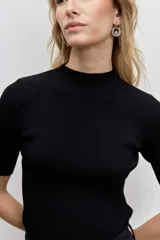 Blusa de punto acanalado en color negro, con cuello alto y mangas cortas ajustadas.