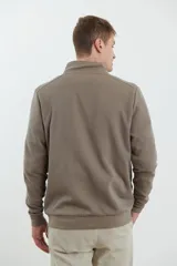 Cardigan de tejido de punto color verde militar, con cierre frontal de metal y cuello redondo. Presenta detalle de tejido plano en la cartera del cierre y en los bolsillos laterales.