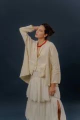 Chaqueta de lino color beige, de calce relajado, con escote en V, cierre frontal con botones y bolsillos frontales aplicados.