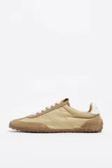 Zapatilla deportiva confeccionada en serraje, con detalle trasero en piel y suela de caucho con cuña interna.