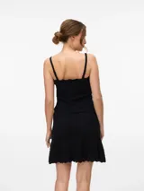 Top negro sin mangas, con tirantes finos y escote cuadrado con borde festoneado. Presenta una hilera de botones frontales y tejido de punto con patrón en zigzag.