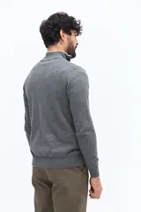 Sweater de tejido liso color verde oscuro, con cuello medio y cierre frontal parcial plateado. Presenta puños y cintura acanalados, y un pequeño logo bordado en el pecho.