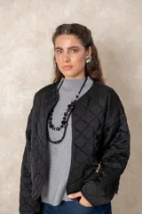 Campera corta de diseño capitoneado con patrón de rombos, color negro. Presenta cuello redondo, cierre frontal abierto, mangas largas y dos bolsillos delanteros con detalle de broche.