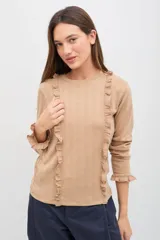 Remera de manga larga color beige con volados verticales en el frente y terminaciones delicadas en los puños. Confeccionada en tejido suave con textura.