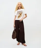 Pantalón de punto estilo aladino, color marrón oscuro, con diseño de tejido calado, cintura elástica y puños ajustados en los tobillos.