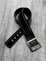 Cinto negro de cuero con tachas plateadas y hebilla cuadrada metálica.