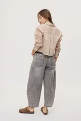 Jean de tiro medio y corte barrel con pierna amplia y ligeramente curva, estilo de cinco bolsillos en denim negro lavado.