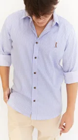 Camisa celeste y blanca a rayas verticales, de corte clásico, con cuello italiano, mangas largas con puños abotonados y logo bordado en el pecho.