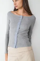 Camiseta de manga larga gris con cuello redondo amplio y cierre frontal de botones celestes a contraste.