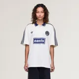 Camiseta Adidas Originals x Oasis de manga corta, color blanco con detalles en azul marino. Presenta cuello polo, las tres tiras características de la marca en los hombros, el logo del trifolio y un estampado frontal con la inscripción "oasis".