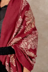 Pashmina de tela densa y suave, con caída pesada y diseño bordado con motivos florales en tonos dorados y beige. Presenta terminaciones con flecos en los extremos.