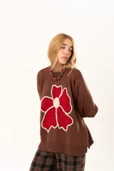 Buzo de punto color chocolate con diseño de flor grande en el frente en tonos rojos y centro texturizado en color crema. Presenta cuello redondo, mangas largas y puños y ruedo acanalados.