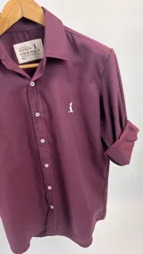 Camisa lisa color vino tinto, de manga larga con puños arremangados, cuello italiano y cierre frontal con botones.