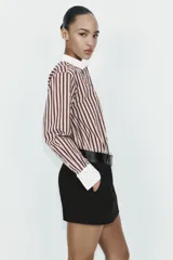 Camisa de manga larga con estampado de rayas verticales en tonos marrón y beige. Presenta cuello solapa y puños anchos en color blanco a contraste, con cierre frontal de botones.