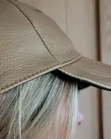 Gorra tipo visera confeccionada en cuero con textura de pelo, diseño clásico con ojales metálicos de ventilación y ajuste posterior.